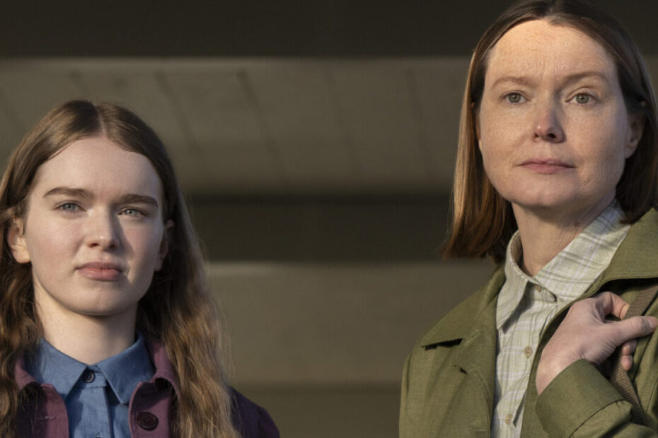 Quando Mike Flanagan decide colocar as mãos em um clássico do suspense e do terror, qualquer pessoa que aprecia uma boa narrativa televisiva sabe que as peças no tabuleiro vão se mover de maneira calculada. A nova adaptação de Carrie, lançada pelo Prime Video com todos os seus oito episódios disponíveis de uma vez, chegou virando a mesa das expectativas. Esqueça a fórmula batida de choque gratuito: o que temos aqui é uma reconstrução meticulosa, psicológica e muito mais perigosa sobre dinâmica familiar, segredos institucionais e traumas reprimidos. Quando Mike Flanagan decide colocar as mãos em um clássico do suspense e do terror, qualquer pessoa que aprecia uma boa narrativa televisiva sabe que as peças no tabuleiro vão se mover de maneira calculada. A nova adaptação de **Carrie**, lançada pelo Prime Video com todos os seus oito episódios disponíveis de uma vez, chegou virando a mesa das expectativas. Esqueça a fórmula batida de choque gratuito: o que temos aqui é uma reconstrução meticulosa, psicológica e muito mais perigosa sobre dinâmica familiar, segredos institucionais e traumas reprimidos. A história nos situa imediatamente após a catástrofe em Chamberlain, no Maine. A cidadezinha está em ruínas, com a escola e metade da vizinhança consumidas pelas chamas. Logo no início, somos jogados no depoimento tenso de Sue Snell, que conversa com um interlocutor misterioso tentando justificar o injustificável ao afirmar que eles eram apenas crianças tentando fazer o melhor que podiam. Mas, como qualquer bom jogo de poder nos ensina, boas intenções raramente evitam o colapso. ## **A quebra do isolamento: da tragédia familiar ao choque com a realidade** Diferente de versões anteriores, a série estabelece sua ruptura logo nos primeiros minutos. Vemos Ralph White partindo para mais um dia de trabalho na construção civil, o exato dia em que sua morte trágica em um acidente de trabalho destrói a redoma da família White. Com o falecimento do patriarca, Margaret White (interpretada por Samantha Sloyan) e a jovem Carrie (Summer H. Howell) ficam totalmente desprotegidas contra o mundo exterior. O primeiro contato das autoridades com essa realidade é estarrecedor: policiais e assistentes sociais invadem a residência e encontram mãe e filha encolhidas dentro de um armário, escondendo-se dos intrusos e do restante da humanidade. A assistente social do caso descreve o núcleo como uma "seita de três pessoas". O lar dos White não possuía telefones, televisão, acesso à internet ou qualquer janela para as notícias do mundo moderno. Carrie cresceu completamente desinformada, mas, de forma surpreendente, extremamente curiosa e aberta à vida. Margaret também surge inicialmente sob a ótica de vítima, alguém que não cruzava a própria porta há anos. Contudo, a burocracia do mundo real não tolera o isolamento absoluto por muito tempo. Com a ausência definitiva do marido, as leis locais entram em ação: a mãe precisa arranjar um emprego e a filha adolescente é obrigada a frequentar a escola pública. ## **Uma relação materna construída no afeto antes da inevitável traição** A dinâmica entre Margaret e Carrie ganha contornos muito mais sofisticados sob o roteiro e a direção de Mike Flanagan. Enquanto a versão icônica de 1976 dirigida por Brian De Palma, eternizada pela atuação de Piper Laurie, focava em uma mãe fria e abertamente aterrorizante desde o primeiro segundo, Samantha Sloyan teve a missão de partir de um ponto emocional completamente diferente: o amor genuíno. Sloyan revelou que essa abordagem inicial foi pensada exatamente para potencializar o impacto dramático da história. Segundo a atriz, Flanagan escreveu essa relação focando na cumplicidade entre mãe e filha para que, quando Margaret inevitavelmente falha e se torna ausente nos momentos em que Carrie mais precisa de amparo, a dor da traição seja devastadora para o público e para a garota. Ao mesmo tempo, Sloyan fez questão de resgatar elementos viscerais da atuação de Laurie, garantindo que o perigo constante que Margaret representa nunca desaparecesse sob a camada de afeto. Do outro lado desse conflito silencioso está a novata Summer H. Howell. A jovem atriz imprime em Carrie uma sede vibrante de viver. Diferente do arquétipo puramente apático do passado, esta versão da protagonista quer ler, digitar nos computadores, conhecer pessoas e absorver o universo que lhe foi roubado durante anos. Ela encara a saída do armário não com repulsa, mas com gratidão e deslumbramento — até que o sistema começa a ruir. ## **O gatilho do caos: simulação de tiroteio, poderes telecinéticos e tabus biológicos** A chegada de Carrie ao ambiente escolar é um choque brutal de realidades. Enquanto a garota tenta se adaptar e demonstra entusiasmo pelo aprendizado, um treinamento contra atiradores ativos transforma sua inocência em puro pânico. Sem entender que se tratava de uma mera simulação, Carrie entra em choque profundo. Esse medo descontrolado serve como fagulha para o despertar inegável de suas habilidades telecinéticas: a tensão psíquica da jovem faz com que uma televisão de tela plana seja arrancada da parede da sala de aula. Para o professor, o senhor Peist, tratou-se apenas de um tremor de terra inexplicável. A reação de Margaret a esse episódio expõe as garras que a mãe tentava esconder. Ela invade a sala do diretor Henry Grayle com autoridade implacável, repreendendo a escola pela negligência e deixando claro que sua filha jamais participará de novos exercícios desse tipo. Enquanto a mãe trava essa batalha na diretoria, o destino cobra um preço altíssimo de Carrie no vestiário feminino. Durante a aula de educação física, a jovem menstrua pela primeira vez. Sem nenhuma educação biológica e mantida em total ignorância religiosa pela mãe, Carrie entra em desespero absoluto, crente de que está sangrando até a morte diante de suas colegas. ## **O mistério se expande: novos elementos psíquicos e o aviso de Sue Snell** Se a tragédia do vestiário já parecia o ápice do drama, Flanagan adiciona uma carta surpreendente ao baralho. No momento exato em que Carrie entra em colapso emocional na escola, uma jovem completamente desconhecida, em outro local distante, começa a sentir todas as dores físicas e mentais da protagonista. As mãos dessa figura misteriosa chegam a ficar cobertas de sangue como se compartilhassem uma ligação empática direta com Carrie. Essa conexão inexplicável se conecta perfeitamente ao mistério narrativo proposto no interrogatório do início. Ao revisitar as memórias da destruição de Chamberlain, Sue Snell alerta quem quer que esteja investigando o caso de que o público está fazendo as perguntas erradas ao focar exclusivamente na garota White. Havia estranhos na cidade que ninguém nunca tinha visto antes, e as cinzas da tragédia guardam segredos muito maiores do que um mero surto adolescente. Como a própria Sue sentencia com firmeza: aquilo não foi apenas obra de Carrie. O Prime Video entrega assim um tabuleiro recheado de peças imprevisíveis, unindo o peso psicológico das relações familiares a um enigma paranormal que desafia tudo o que já sabíamos sobre a clássica história de terror.